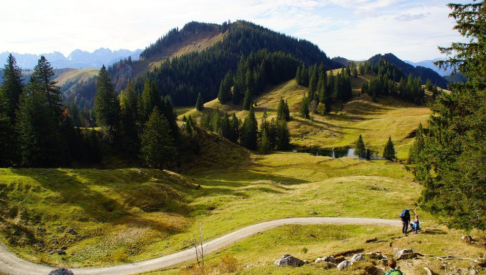 Priener Hütte Berlandschaft Was für ein Glück! Vor Wochen planten wir gemeinsam mit unseren Freunden einen Ausflug in die Chiemgauer Alpen. Eine Familienwanderung zur kinderfreundlichen Priener Hütte am Geigelstein mit einer Übernachtung. Und genau an diesem Wochenende zeigte sich der Herbst nochmal von seiner schönsten Seite. Die Sonne strahlte und das Thermometer zeigte 15 Grad. Die Kinder waren bestens gelaunt und so stand einem schönen Wandertag nichts im Weg. Die Hütte ist leider kein Geheimtipp mehr, aber wirklich einen Ausflug wert. Über die A8 ging es Richtung Sachrang, Ausfahrt Frasdorf und weiter Richtung Aschau im Chiemgau. Nach knapp einer Stunde parkten wir am großen Parkplatz vor der Ortseinfahrt Sachrang. Gemütlich starteten wir die Tour um 13 Uhr. Unser Plan war vor Einbruch der Dunkelheit auf der Hütte zu sein. Laut Beschilderung sollt der Aufstieg in 3Stunden zu bewältigen sein. Der kinderfreundliche Wanderweg führt über eine breite Forststraße direkt zur Hütte. Es gab immer wieder spannende Abzweigungen durch den Wald. Nach einer Stunde Fußmarsch erkundeten wir den ausgeschilderten Waldweg. Dieser bot viel Abenteuer und Abwechslung für die kleinen Wanderer. Nach einer guten Stunde über Stock und Stein kehrten wir wieder auf den Forstweg zurück. Den Kids hat die Wanderung einen Riesenspaß gemacht. Auch unser Jüngster (3 1/2 Jahre) lief die meiste Strecke ganz allein. Beim Weg durch den Wald führten wir ihn an der Hand, da viele Stellen ziemlich steil für die kleinen Kinderbeinchen waren. Aber er meisterte alles ohne murren und war absolut bei der Sache.