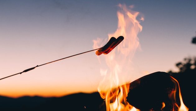 Wurst über dem Feuer braten