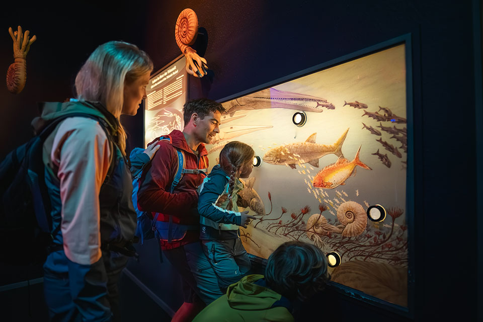 Bergbahn Steinplatte by Klaus Listl Kinder sehen sich, gemeinsam mit ihren Eltern, eine Schautafel mit Fischen und Unterwasser Dions im Triassic Park Steinplatte an.